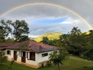 a rainbow over a house with a house at Chalé nas Árvores -Pitayas Agroturismo in Joanópolis