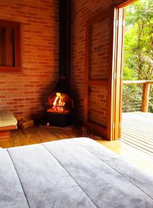 a fireplace in a room with a bed in front of it at Chalé nas Árvores -Pitayas Agroturismo in Joanópolis
