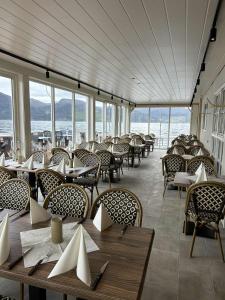 a dining room with tables and chairs and windows at Davik Fjordparadis in Bakken