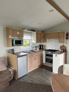 a kitchen with wooden cabinets and white appliances at Meadow lakes golden palm resort in Chapel Saint Leonards