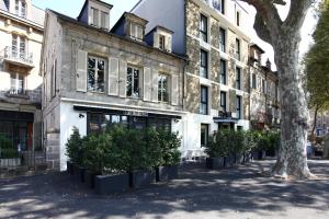 a building with a row of plants in front of it at Hôtel Le Collonges in Brive-la-Gaillarde