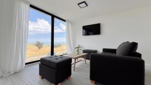 a living room with two chairs and a table and a large window at Marea Baja - Casa con vista al mar para 6 PAX con parrilla en Cruz del Sur, Chapadmalal - Hola Sur in Chapadmalal