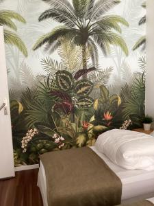 a bedroom with a mural of palm trees and a bed at Les Apparts' Hotel du Canal in Châteaulin