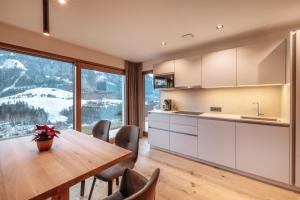 a kitchen with a wooden table and a large window at Resciesa Hof in Ortisei