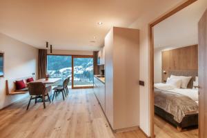 a bedroom with a bed and a table with chairs at Resciesa Hof in Ortisei