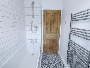 a bathroom with a tub and a wooden door at Shipwrights, 11 Coronation Road in Salcombe +24 photos