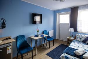 a blue room with a bed and a table and chairs at noclegi u zabki in Ełk