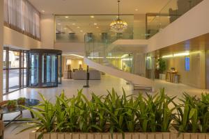 eine Lobby mit einer Treppe in einem Gebäude mit Pflanzen in der Unterkunft Manaíra Hotel in João Pessoa