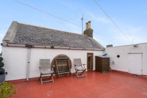 a white building with two chairs on a patio at Creel Cottage, Peterhead in Peterhead