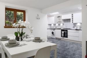 a white kitchen with a white table with flowers on it at Creel Cottage, Peterhead in Peterhead +20 photos