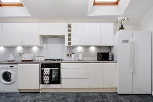 a kitchen with white cabinets and a washer and dryer at Creel Cottage, Peterhead in Peterhead