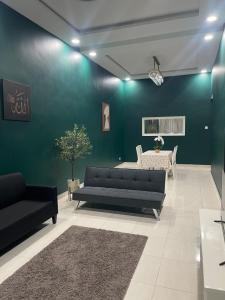 a living room with black couches and a green wall at Nafisa Homestay in Kepala Batas