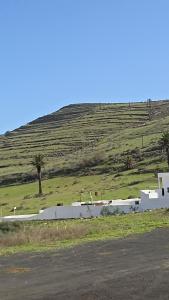 a white building in a field with a hill at Olala House Lanzarote in Haría