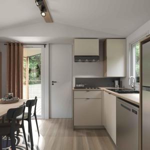 a kitchen with white cabinets and a table with chairs at Camping Loches in Loches +7 photos