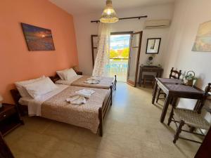 a bedroom with two beds and a table and a window at Tzilios Studios in Acharavi