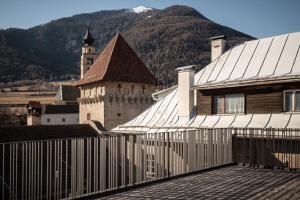 a building with a fence in front of a mountain at flurin Suites in Glorenza