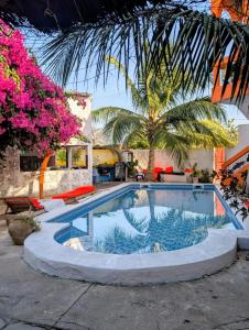 a swimming pool in front of a house with pink flowers at Hôtel évasion pêche djilor île sine saloum in Fatick