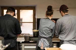 three people standing in a kitchen preparing food at flurin Suites in Glorenza
