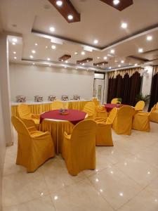 a banquet hall with tables and yellow chairs at Hotel Valentines in Prayagraj