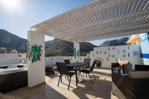 a patio with a table and chairs under a pergola at Stergios top view residence with jacuzzi in Kolymbia
