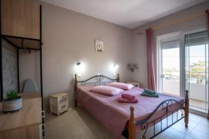a bedroom with a bed with pink pillows and a window at Stergios top view residence with jacuzzi in Kolymbia