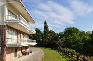 a building with a balcony and a bench in the grass at VILLA ISLAS Urdaibai in Isla Becoa