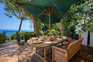 a wooden table with food and an umbrella on a deck at Beachfront Villa Cannes I Garden - Terrace & Sea View -Prime Location- Free Parking in Cannes