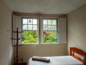 a bedroom with two windows and a bed in it at Casa da Kau in Ouro Preto