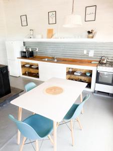 a kitchen with a white table and blue chairs at Mandalas de Mar in Punta Del Diablo