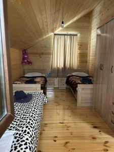 a room with two beds in a wooden cabin at Cottage SUNNY in Itʼkhvisi