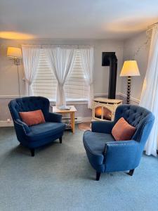 a living room with two blue chairs and a fireplace at The Landgrove in North Landgrove