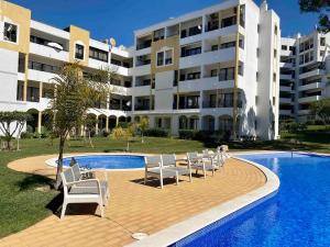 a swimming pool with chairs and a building at Pure Vilamoura 2 bedrooms with pool in Quarteira