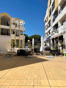 a courtyard with chairs and umbrellas in front of buildings at Pure Vilamoura 2 bedrooms with pool in Quarteira