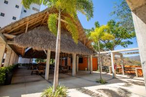 a restaurant with a thatched roof and a palm tree at Alamar Vallarta in Cruz de Huanacaxtle