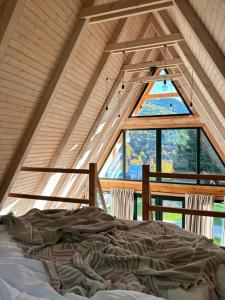 a bed in a room with a large window at A Frames By Pensiunea Merișor in Răchiţele +34 photos