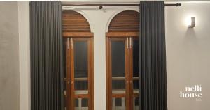 two wooden doors on a wall with a window at nelli house in Galle