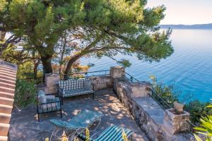 a patio with two chairs and a tree next to the water at House Dobrila in Igrane