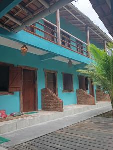 a blue house with a balcony and a palm tree at Pousada Mestre Lua - Itaúnas in Conceição da Barra