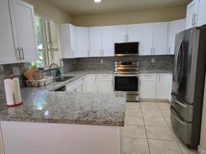 a kitchen with white cabinets and a stainless steel refrigerator at Atlas in Homestead