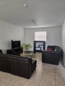 a living room with two leather couches and a tv at Atlas in Homestead