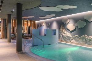 a swimming pool in a building with clouds on the wall at Hotel Zauchensee Zentral in Zauchensee