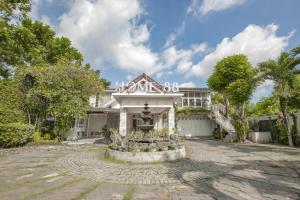 a white house with a fountain in front of it at HOME 88 Feels Like Home in Sleman