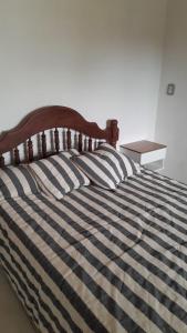 a bed with a black and white striped comforter and a table at La Goldie in Concepción del Uruguay +8 photos