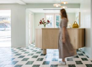 a woman walking in a kitchen with a counter at Bay Shores Peninsula Hotel in Newport Beach