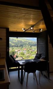 a room with a table and a large window at Fazenda Fishbone, будиночок White fish in Verkhovyna