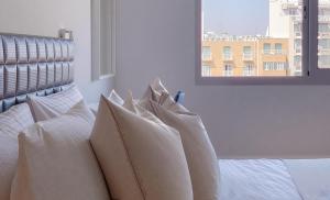 a bedroom with white pillows on a bed with a window at Plateia Suite Brillante in Nicosia