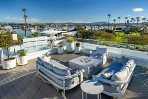 a patio with chairs and a table and a view of a harbor at Bay Shores Peninsula Hotel in Newport Beach