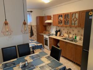 a kitchen with wooden cabinets and a table with chairs at Beni Apartman in Balatonlelle