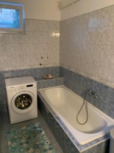 a bathroom with a washing machine next to a bath tub at Beni Apartman in Balatonlelle