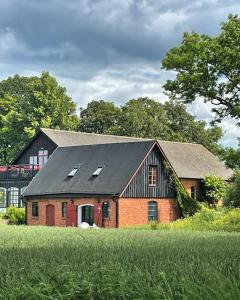 a red barn with a black roof in a field at Fårhuset at Åkarp in Trelleborg